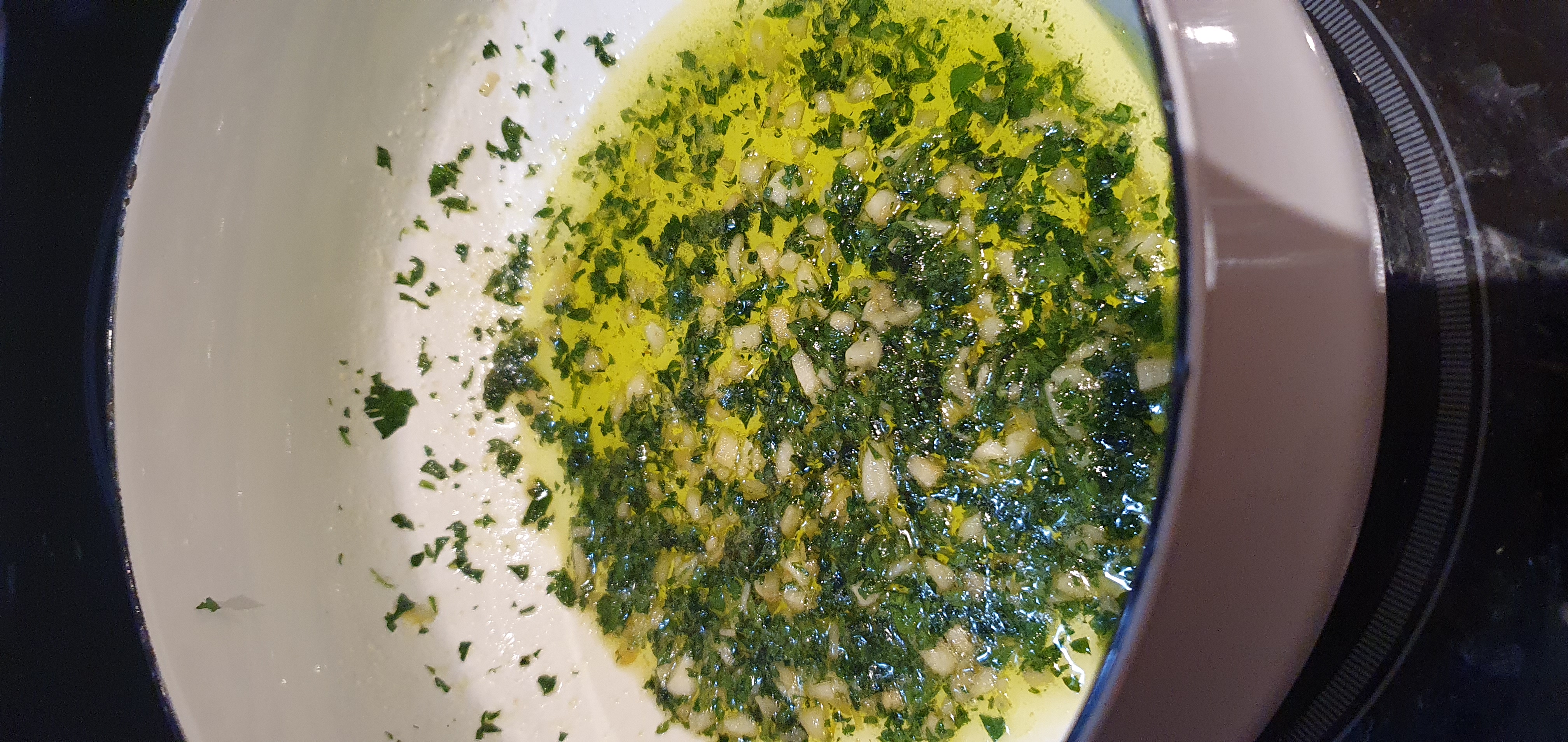 Melted butter with chopped garlic and parsley swirled in a white pan