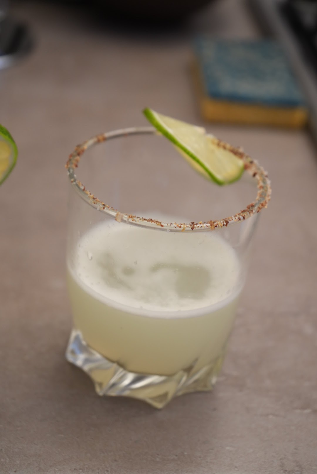 Classic margarita served in a rocks glass with a chili-salt rim and a lime wedge