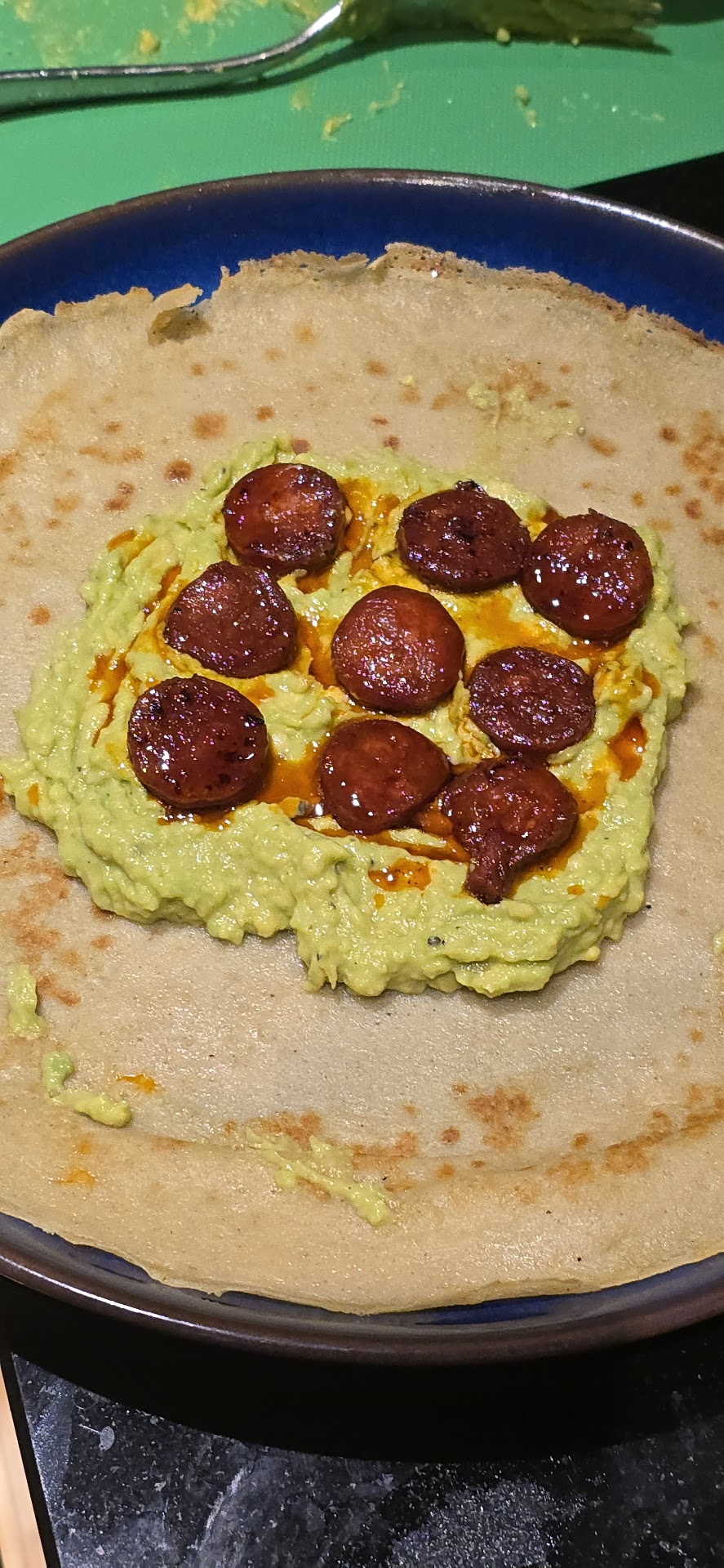 Buckwheat pancake topped with guacamole and slices of crisped chorizo