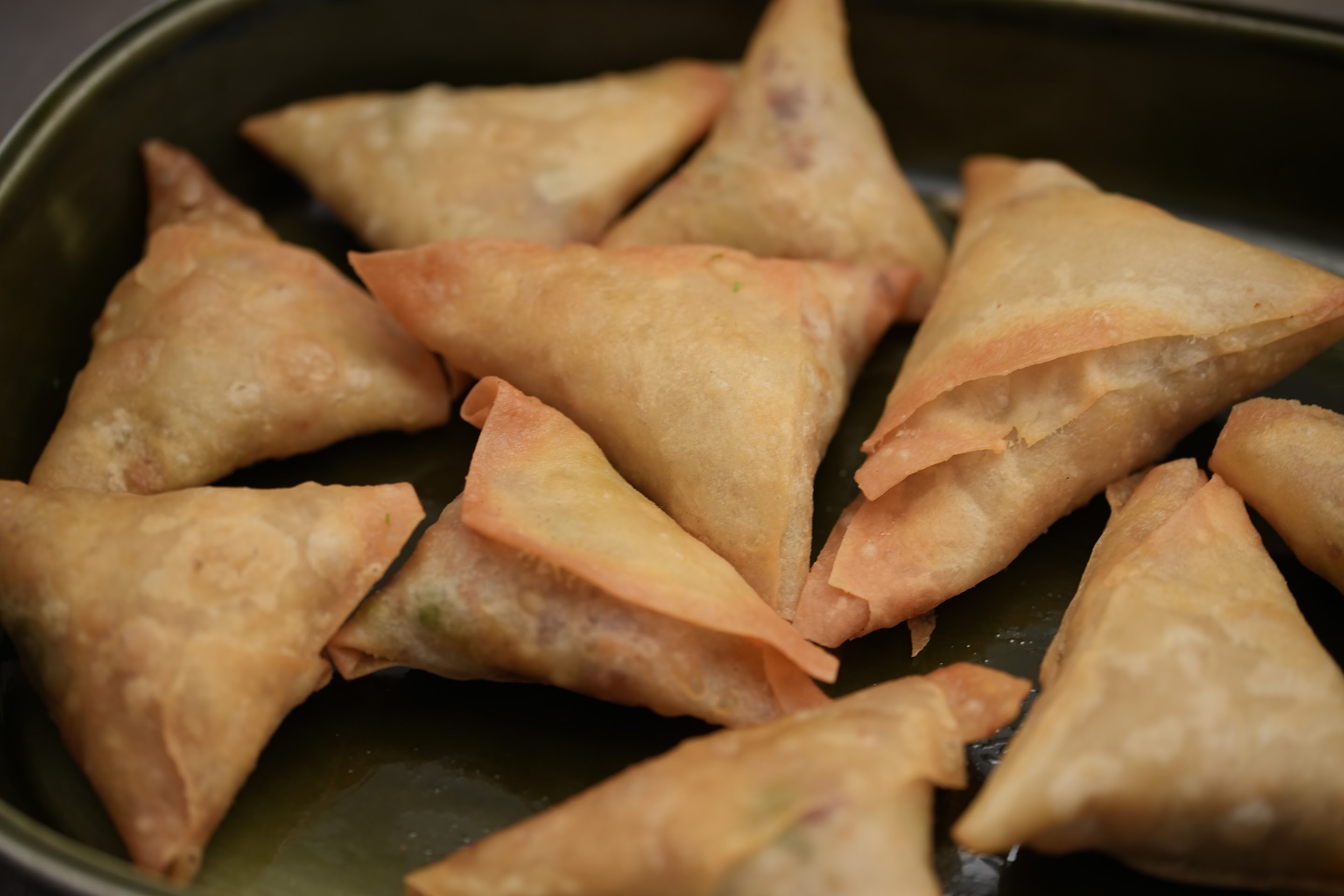 Crisp baked samosas resting in a metal tray